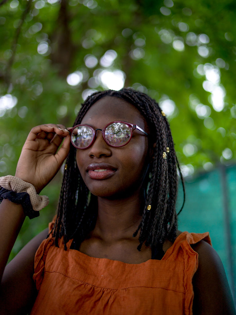 Saly Seye stands underneath the shade of tree